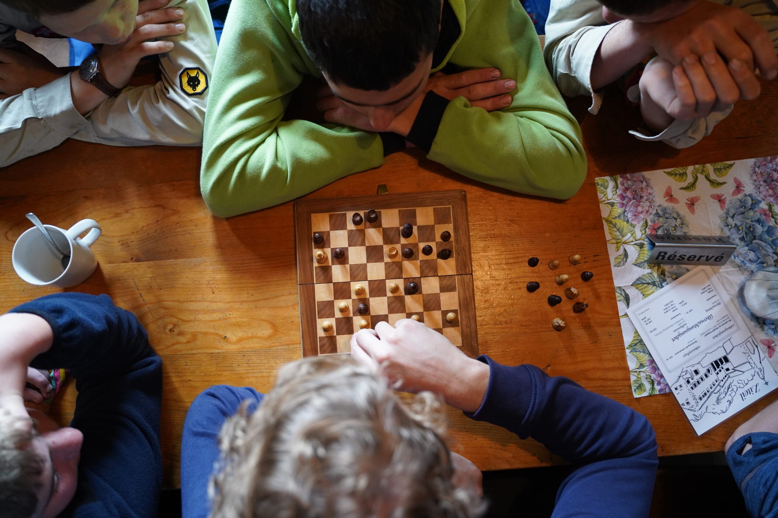 Dieses Bild zeigt eine Gruppe von Pfadfindern, die gemeinsam ein Brettspiel spielen.