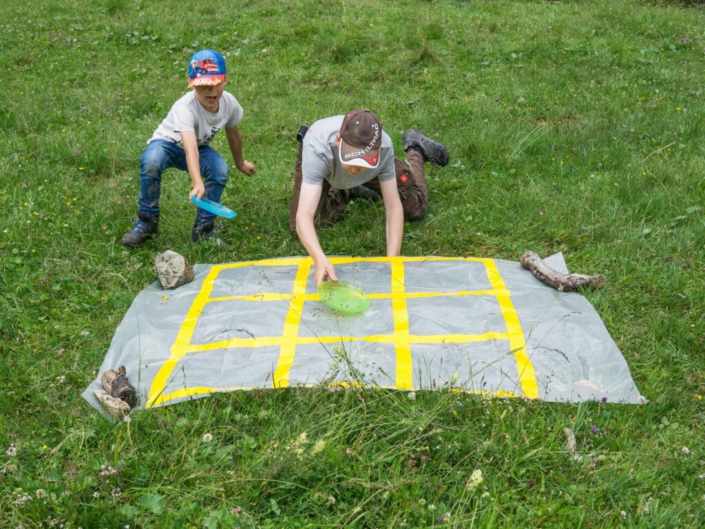 Dieses Bild zeigt zwei junge Pfadfinder, die gemeinsam ein Outdoor-Spiel spielen.