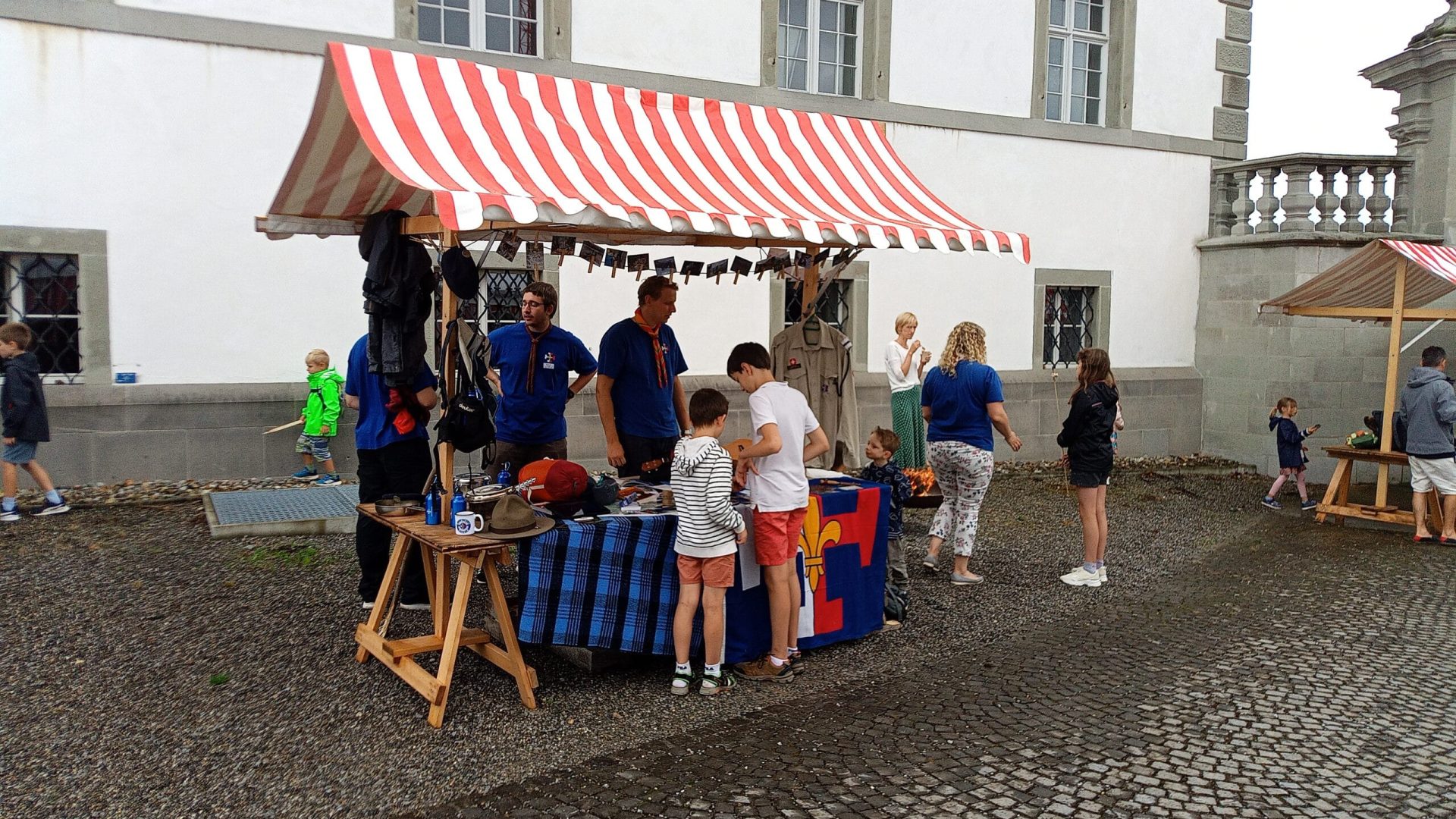 Titelbild für die Seite «Stand und Kinderprogramm am Weltfamilientag in Einsiedeln» (August 2024) Das Bild zeigt Pfadfinder, die einen Stand am Weltfamilientag in Einsiedeln betreuen.